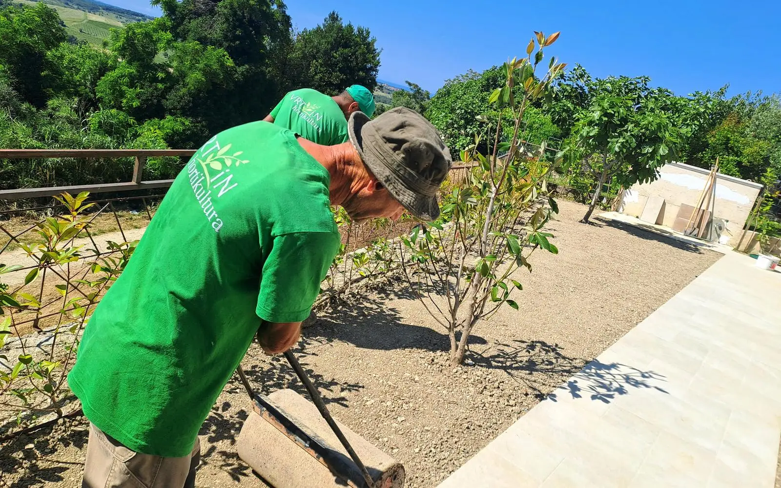 Vrt iN gardeners rolling the ground beside a new path