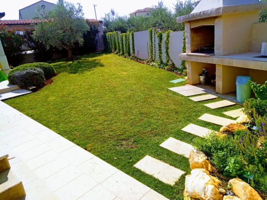 Lawn with stone stepping slabs by an outdoor grill
