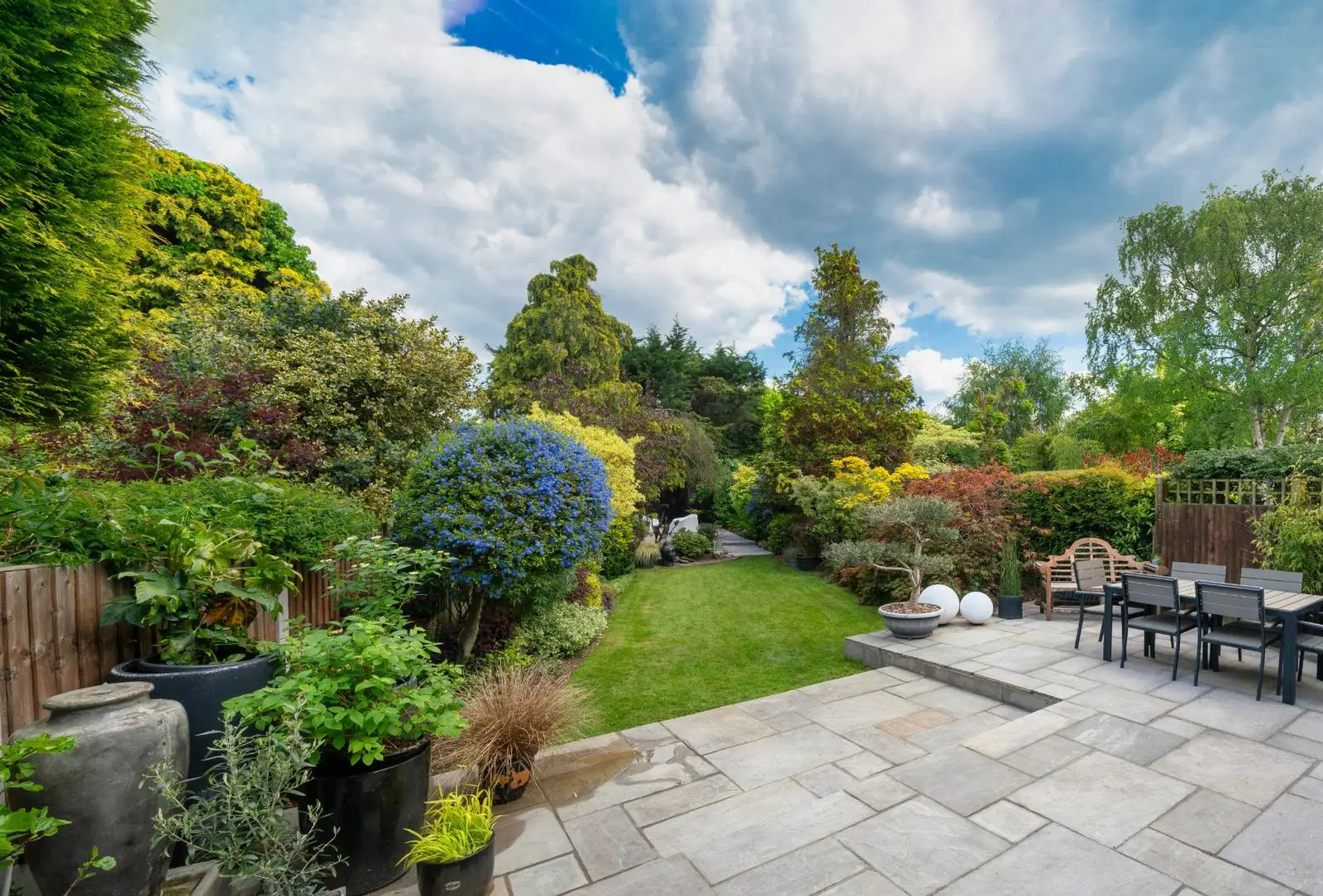 Paved terrace surrounded by shrubs and flower beds