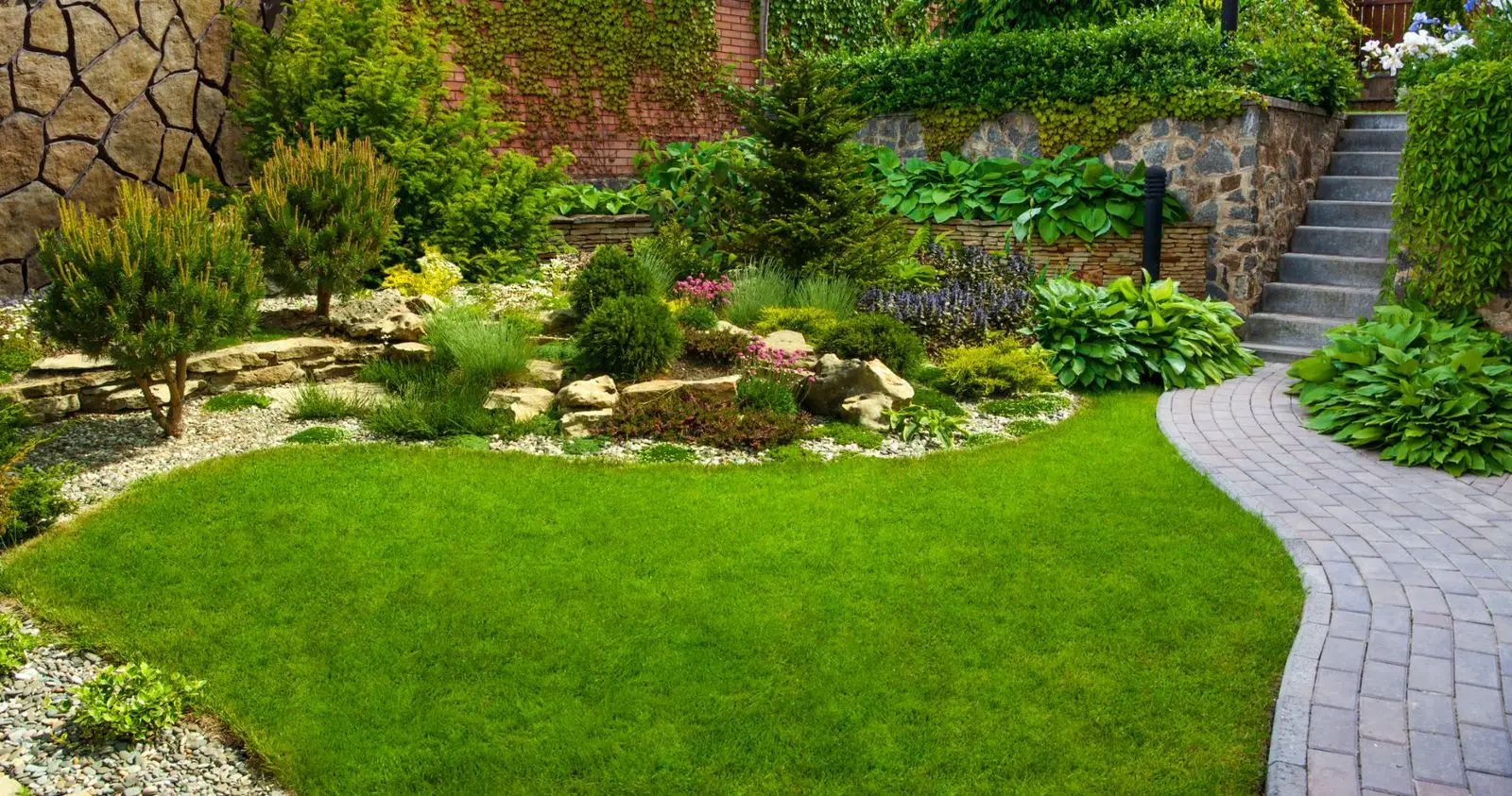 Landscaped garden with a lawn, stone retaining wall and paved path